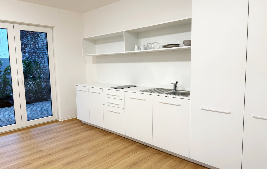 Küchenzeile und Tür zur eigenen Terrasse im Erdgeschoss-Duplex 0.2 des RW63