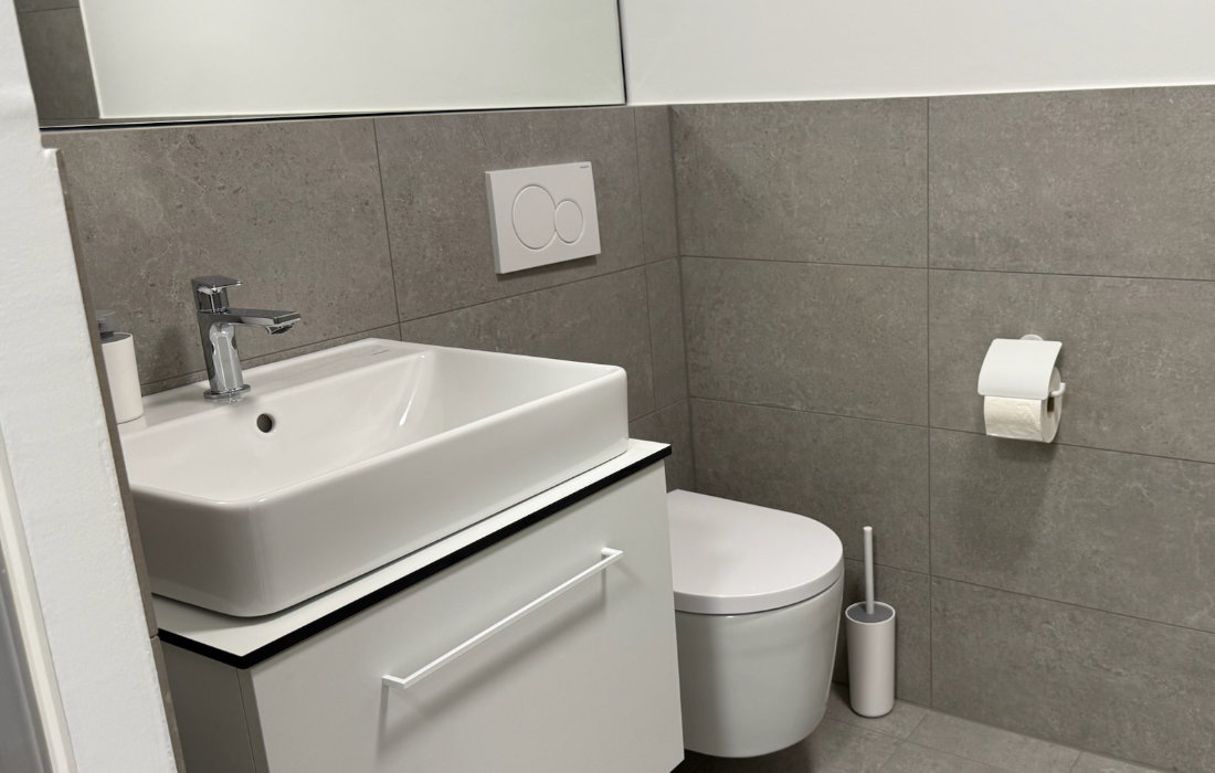 Eigenes Badezimmer eines RW63-Apartments mit Waschtisch, Spiegel und WC