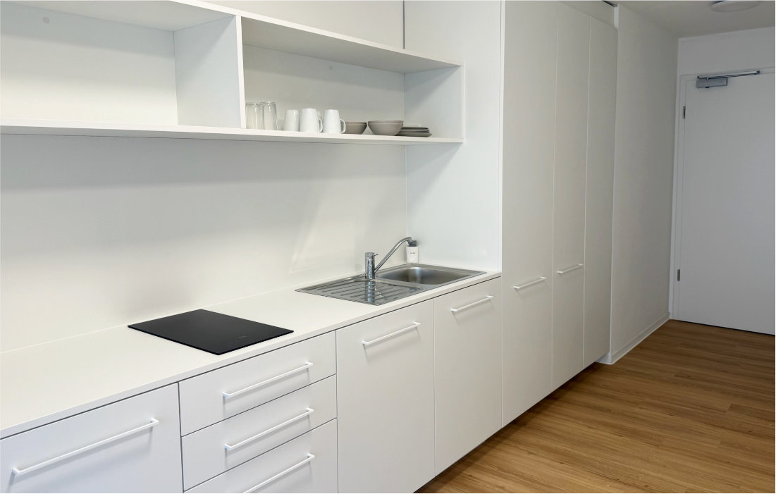 Küchenzeile mit Spüle, Kochfeld und Hängeregal im Single-Apartment 1.4 zum Innenhof
