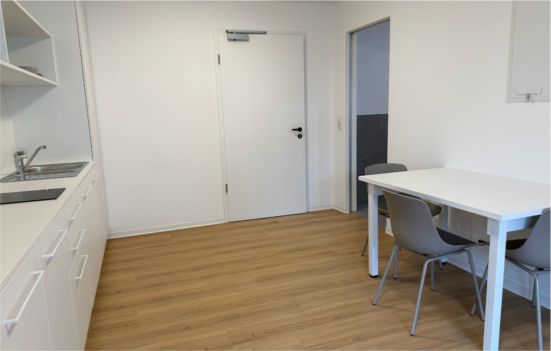 Wohn- und Essbereich mit Küchenzeile, Esstisch und Wohnungstür im Duplex-Apartment 1.5