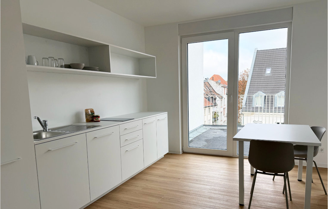 Dachgeschoss-Apartment 6.1 im RW63 mit Küchenzeile, Essplatz und Tür zum eigenen Außenbereich